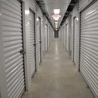 a long hallway filled with rows of storage units with a red exit sign .