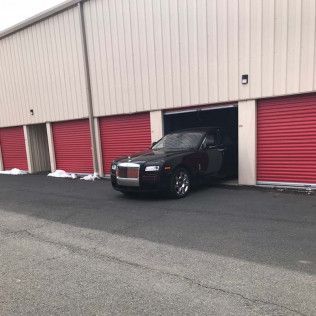 a black rolls royce ghost is parked in a garage .