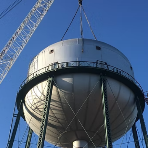 Water tower atop a brown brick building against a partly cloudy blue sky.