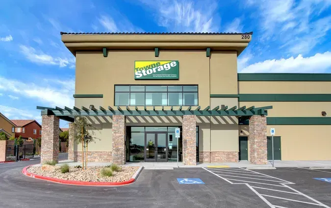 A beige and green self-storage facility building with a stone-pillared entrance under a blue sky.