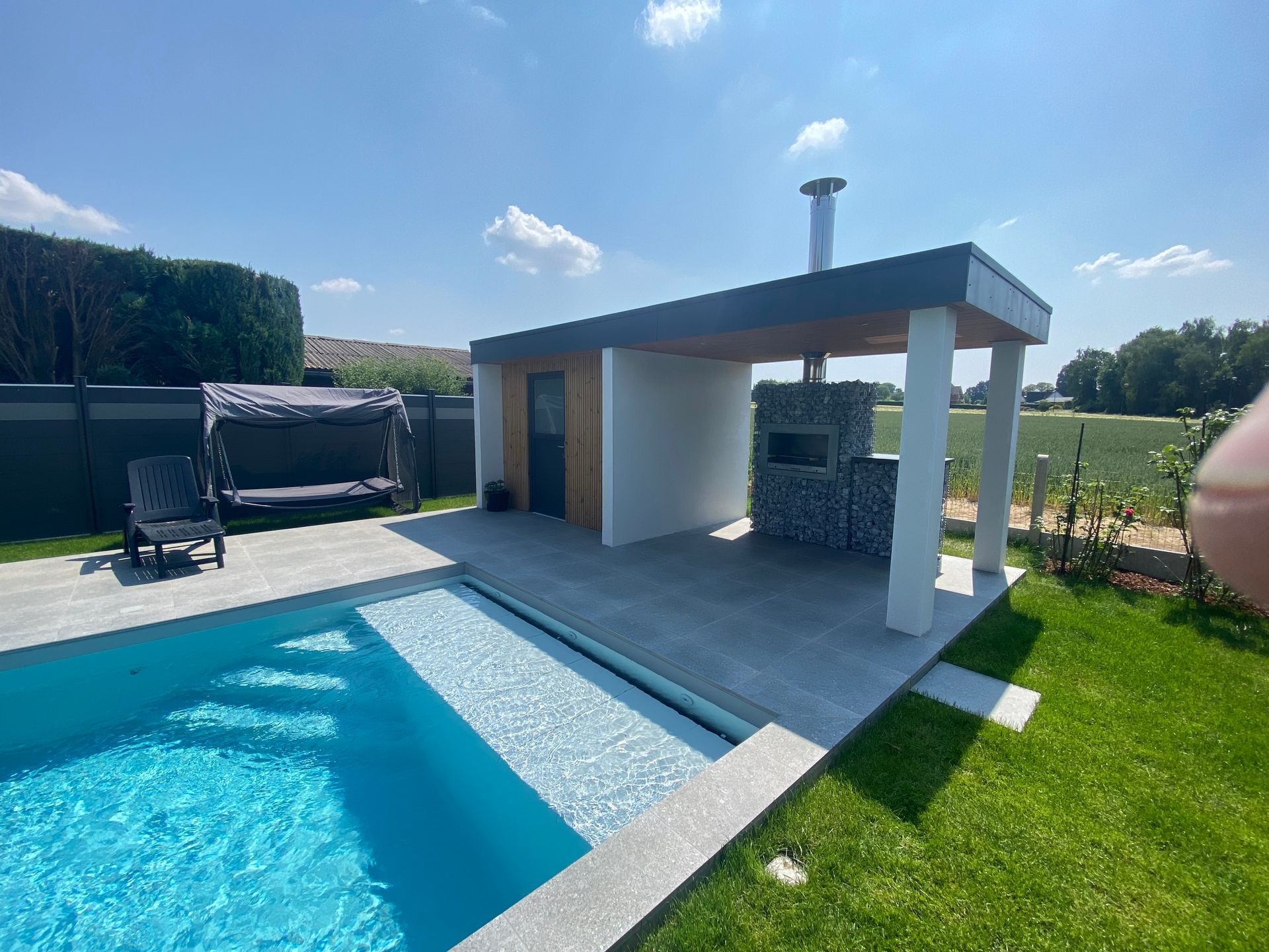 Une piscine avec un gazebo et un grill dans la cour arrière.