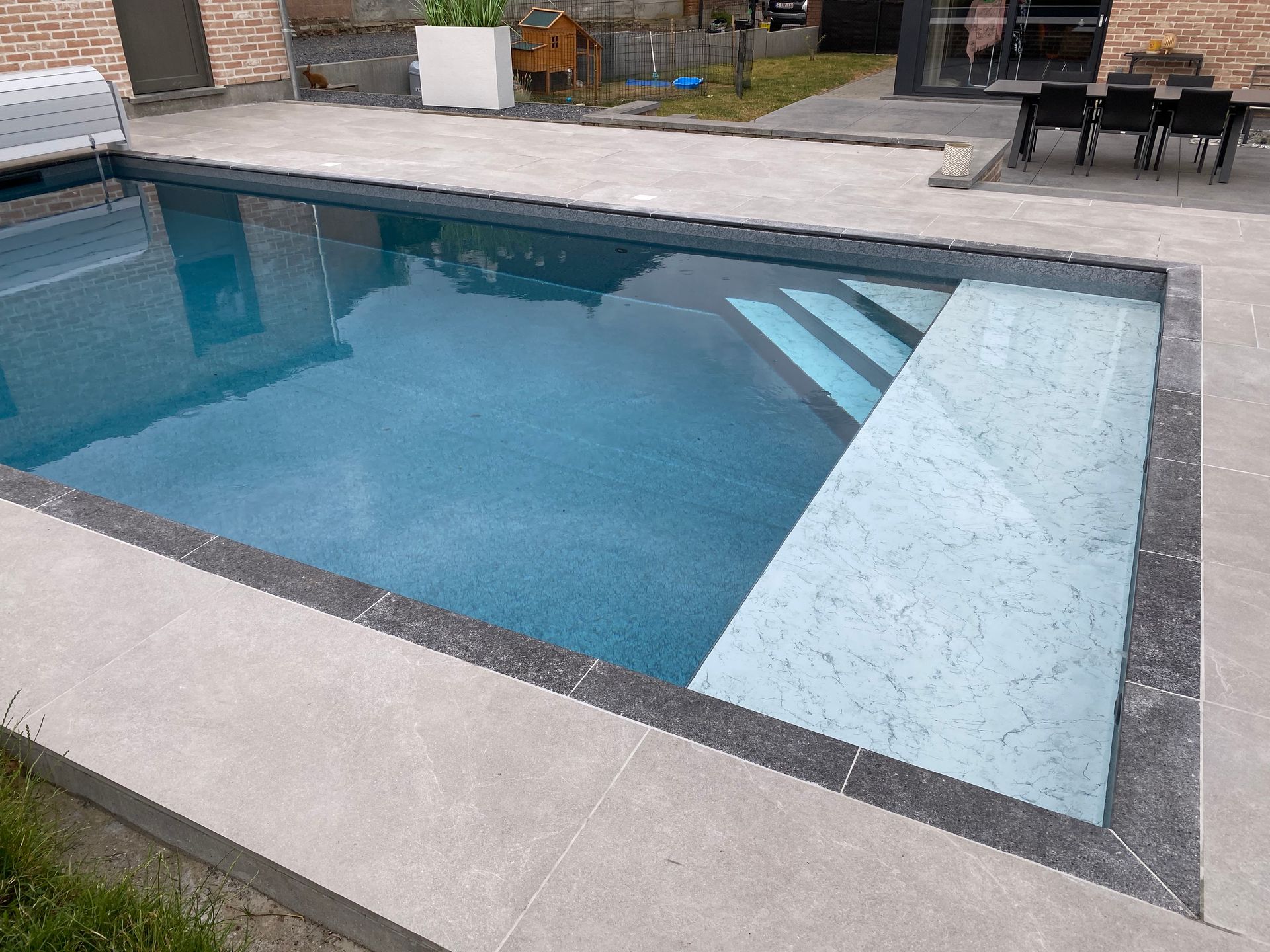 Une grande piscine dans une cour arrière à côté d'une maison.