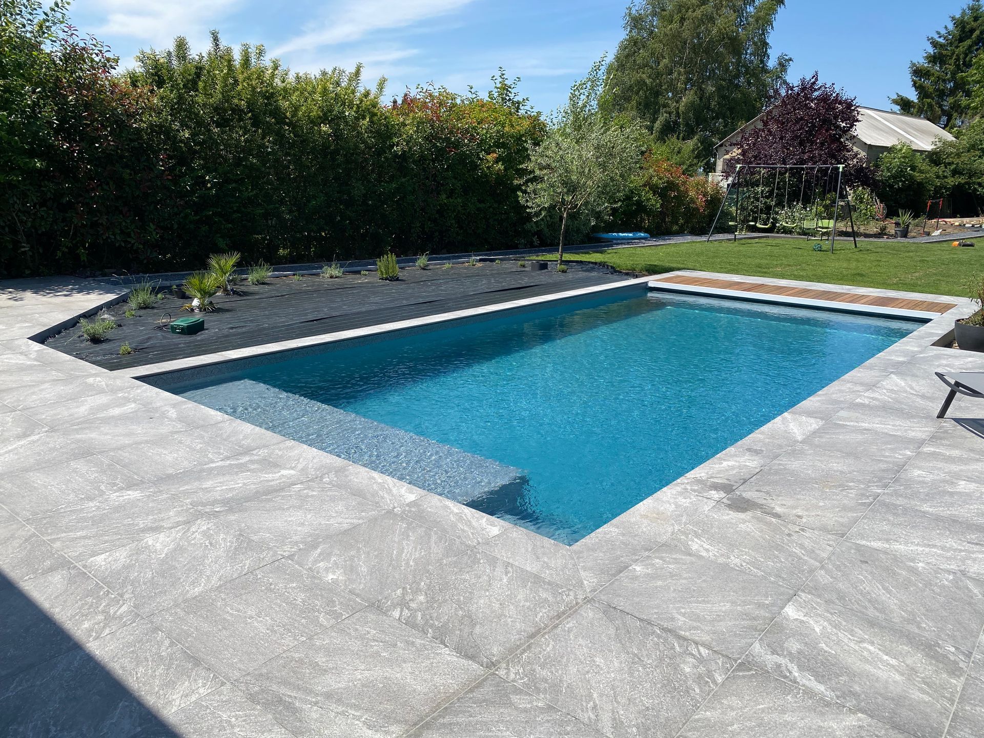 Une grande piscine entourée d'arbres et d'arbustes dans une cour arrière.