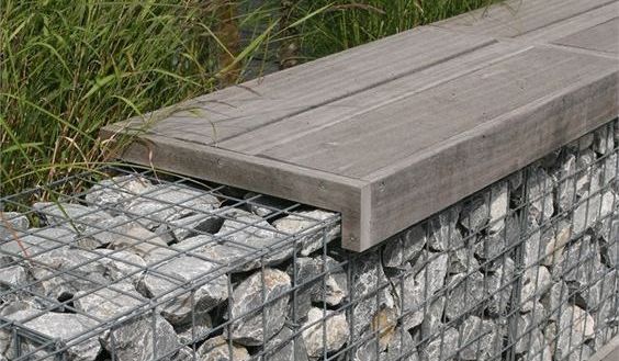 Un banc en bois est assis au sommet d'un mur de pierre.