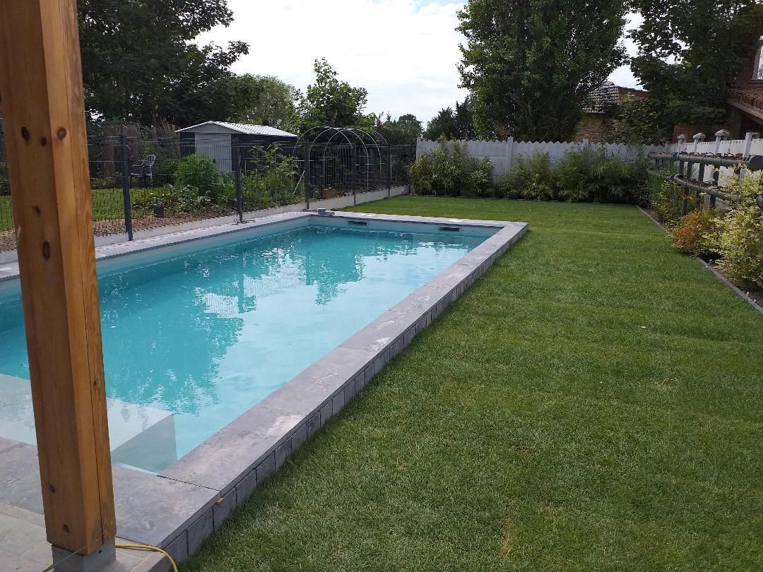 Une grande piscine se trouve au milieu d'une cour verdoyante.