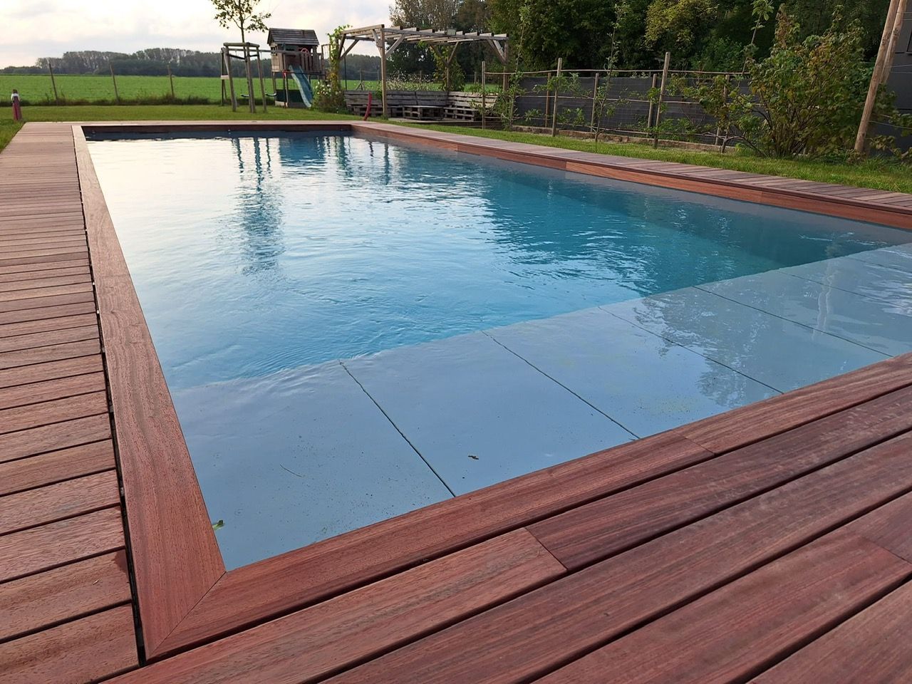 Une grande piscine entourée d'une terrasse en bois.