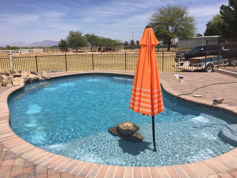 A large swimming pool with an orange umbrella in the middle
