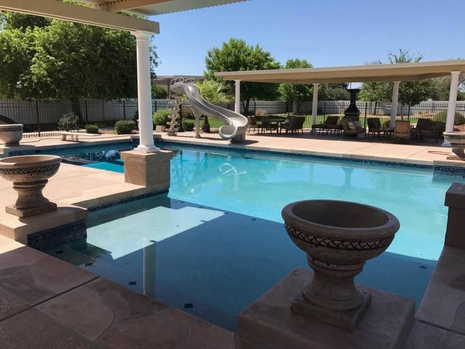A large swimming pool with a slide in the backyard