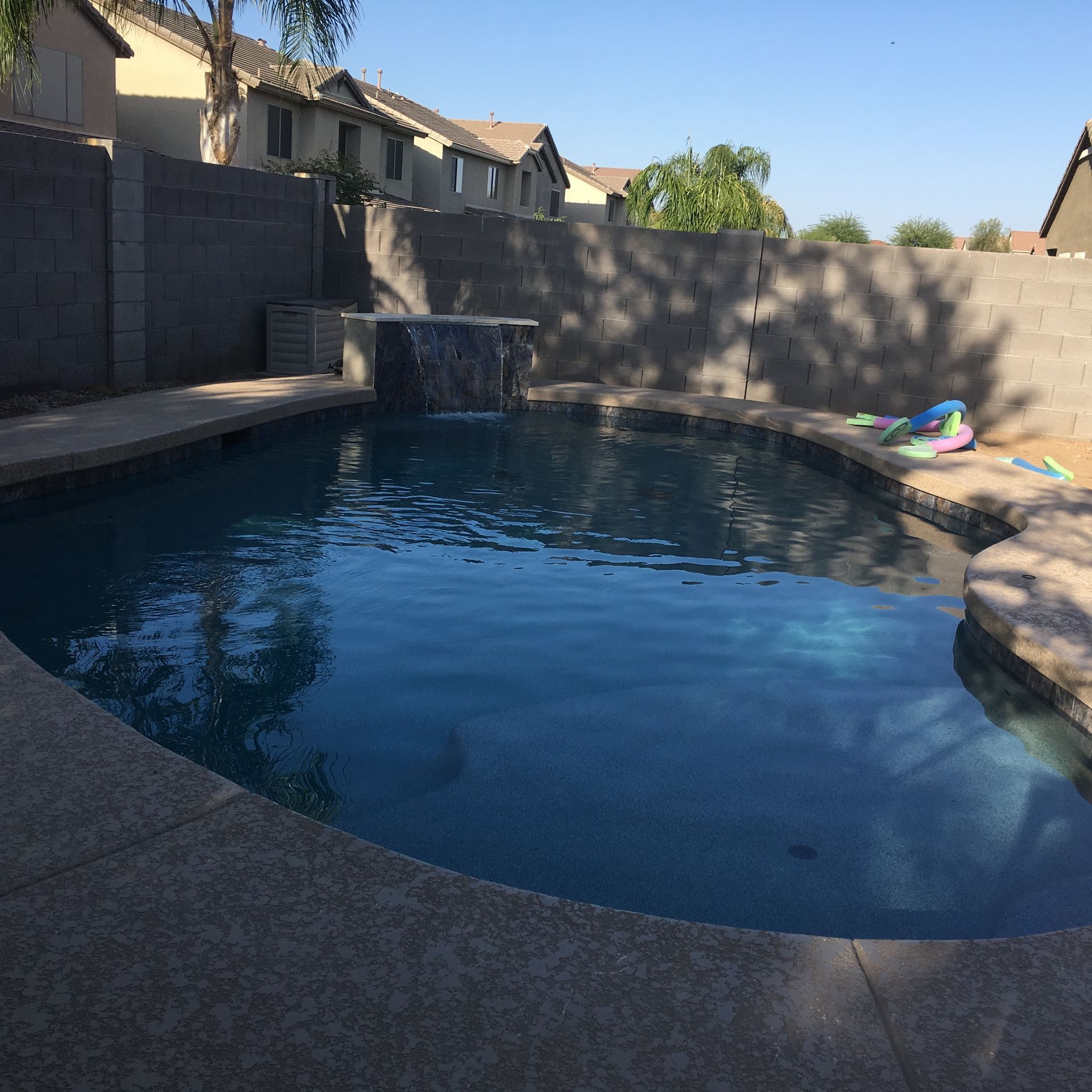 A large swimming pool with a waterfall in the middle