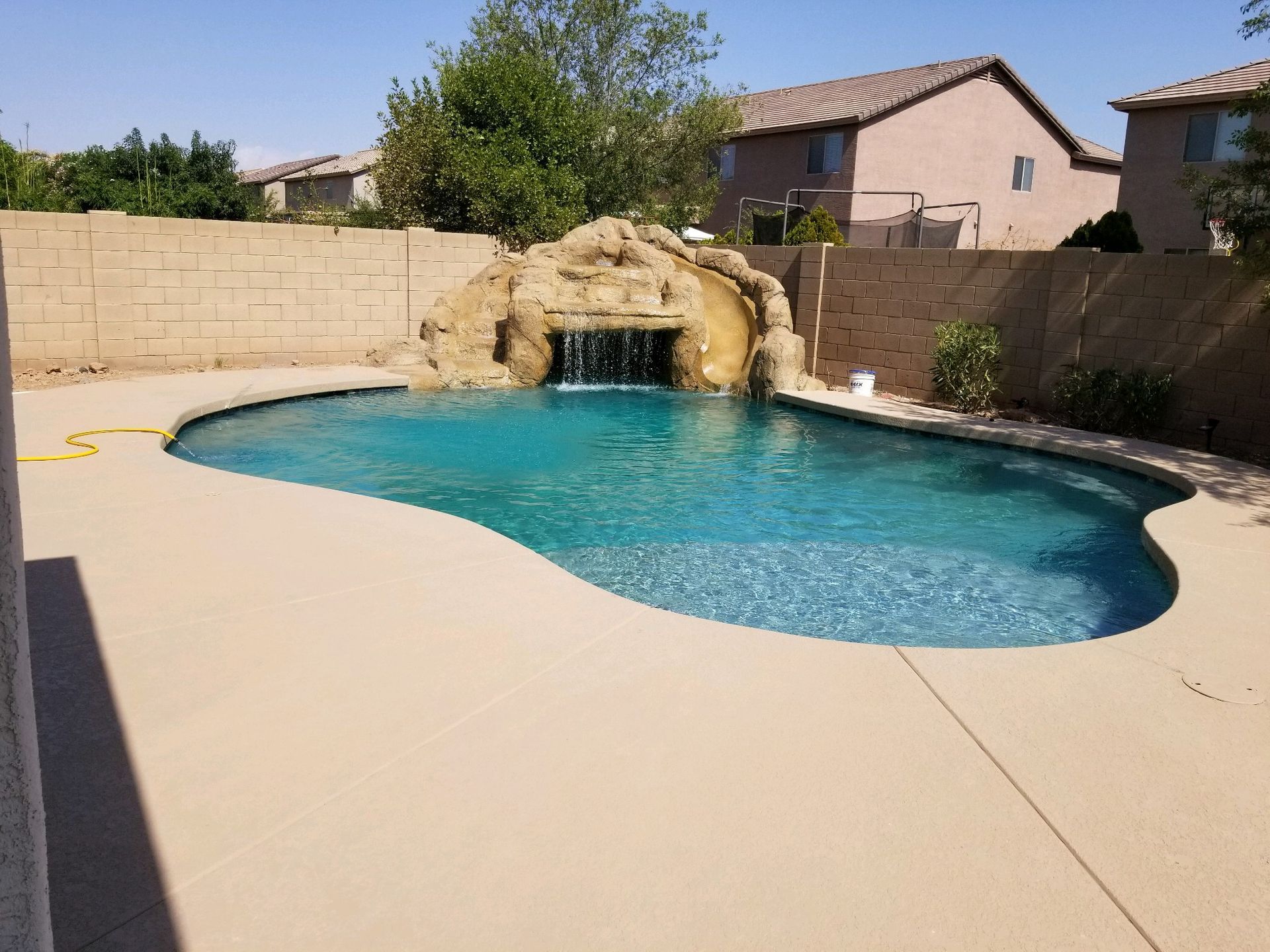 A large swimming pool with a waterfall in the backyard