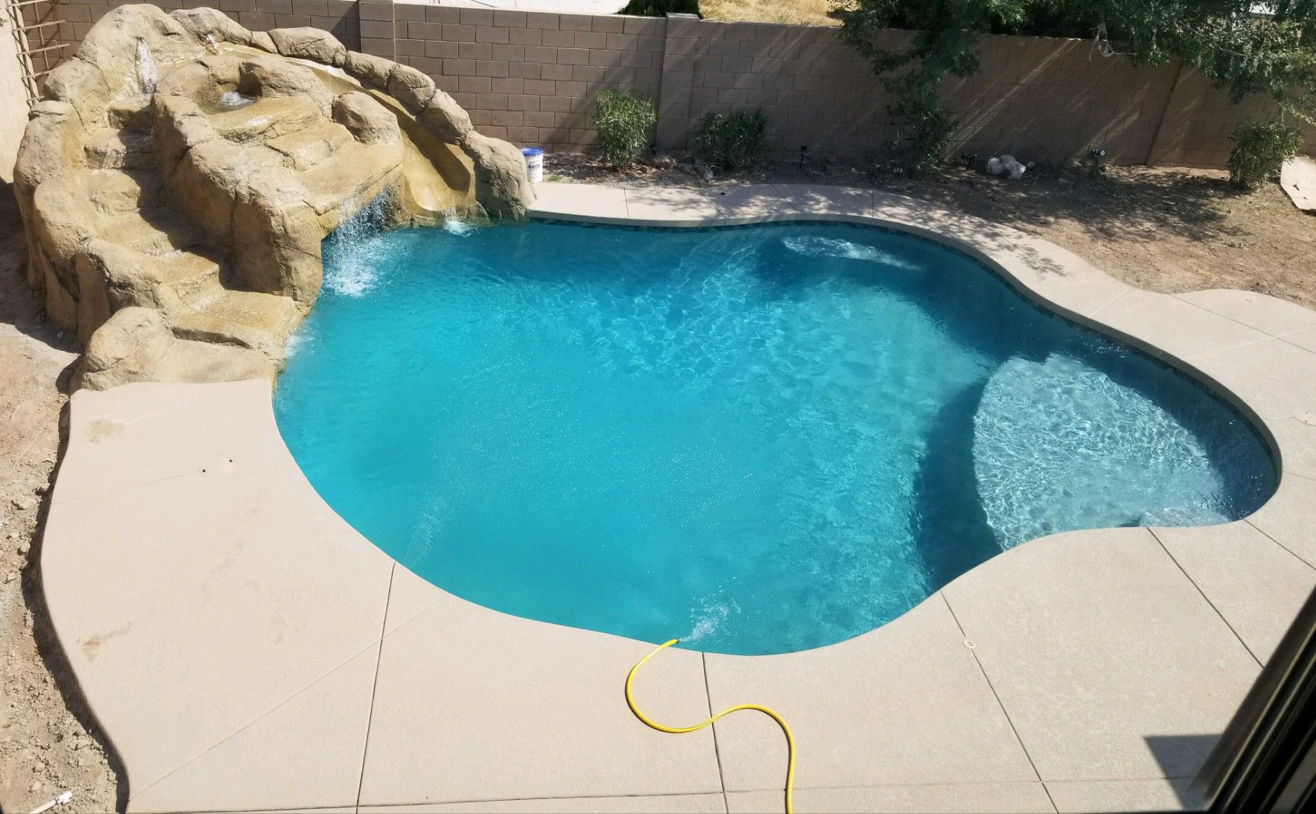A large swimming pool with a water slide in the backyard.