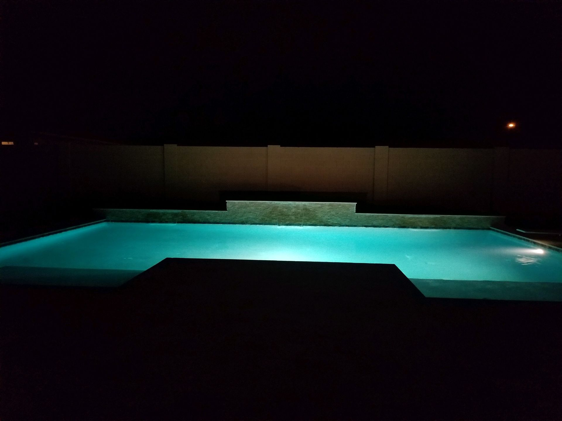 A large swimming pool is lit up at night.