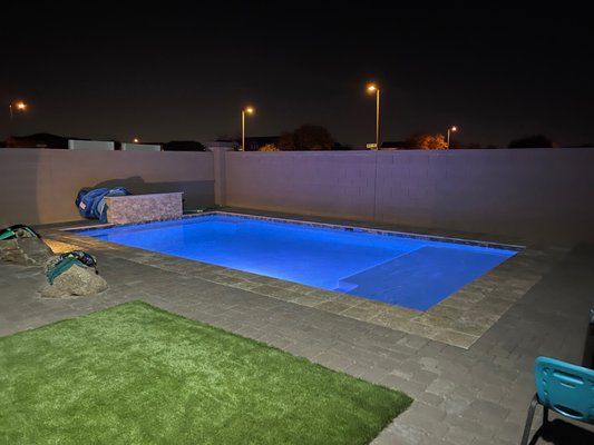 A large swimming pool is lit up at night.