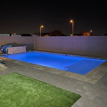 A large swimming pool is lit up at night with blue lights.