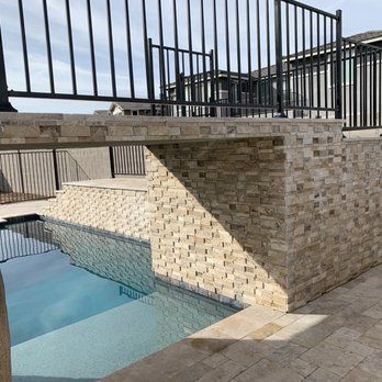 A swimming pool with a brick wall and a fence around it.