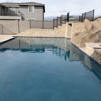 A large swimming pool with a fence around it and a house in the background.