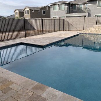 A large swimming pool with a fence around it and houses in the background.