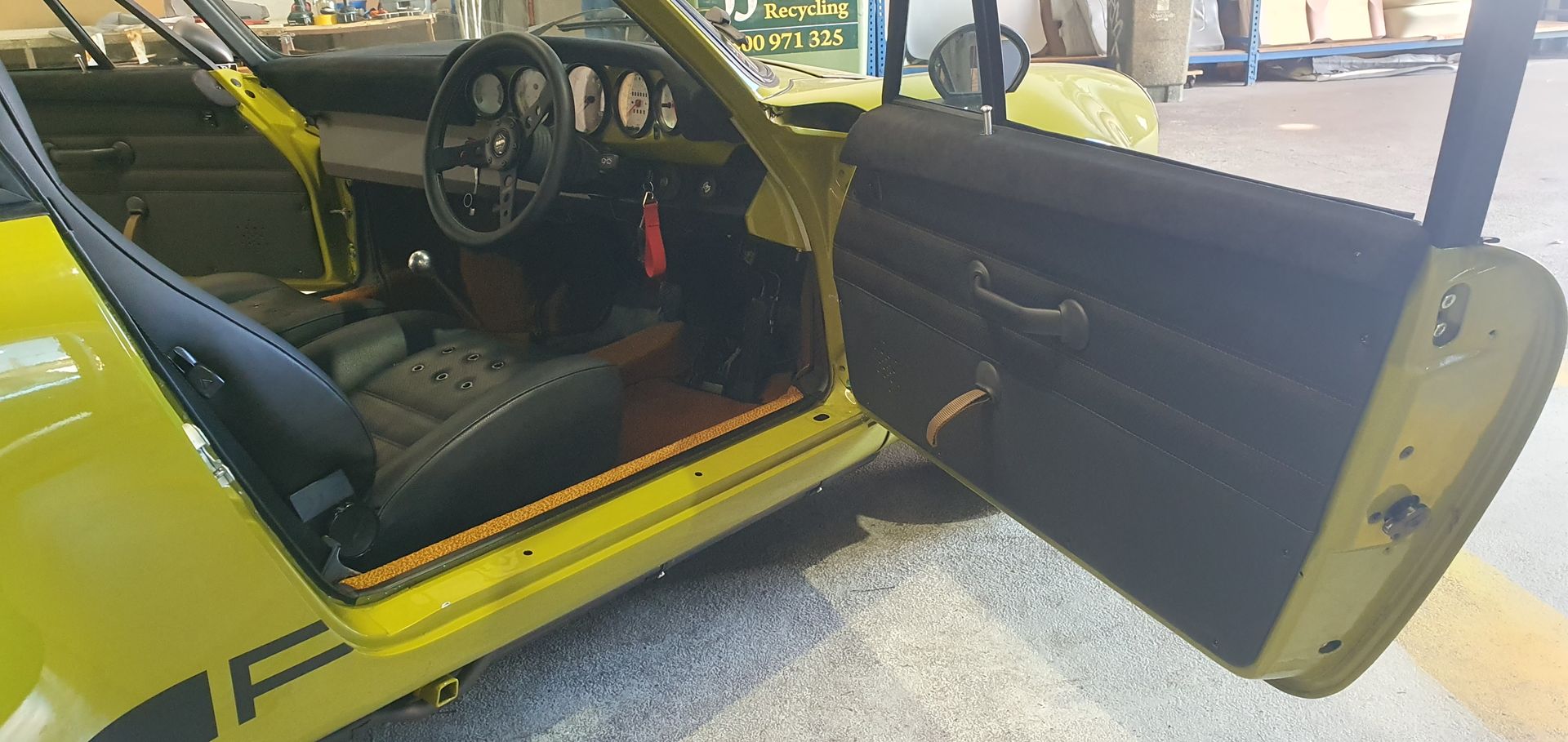 The open driver-side door of a bright yellow vintage sports car — Tidy Trim Newcastle in Carrington, NSW