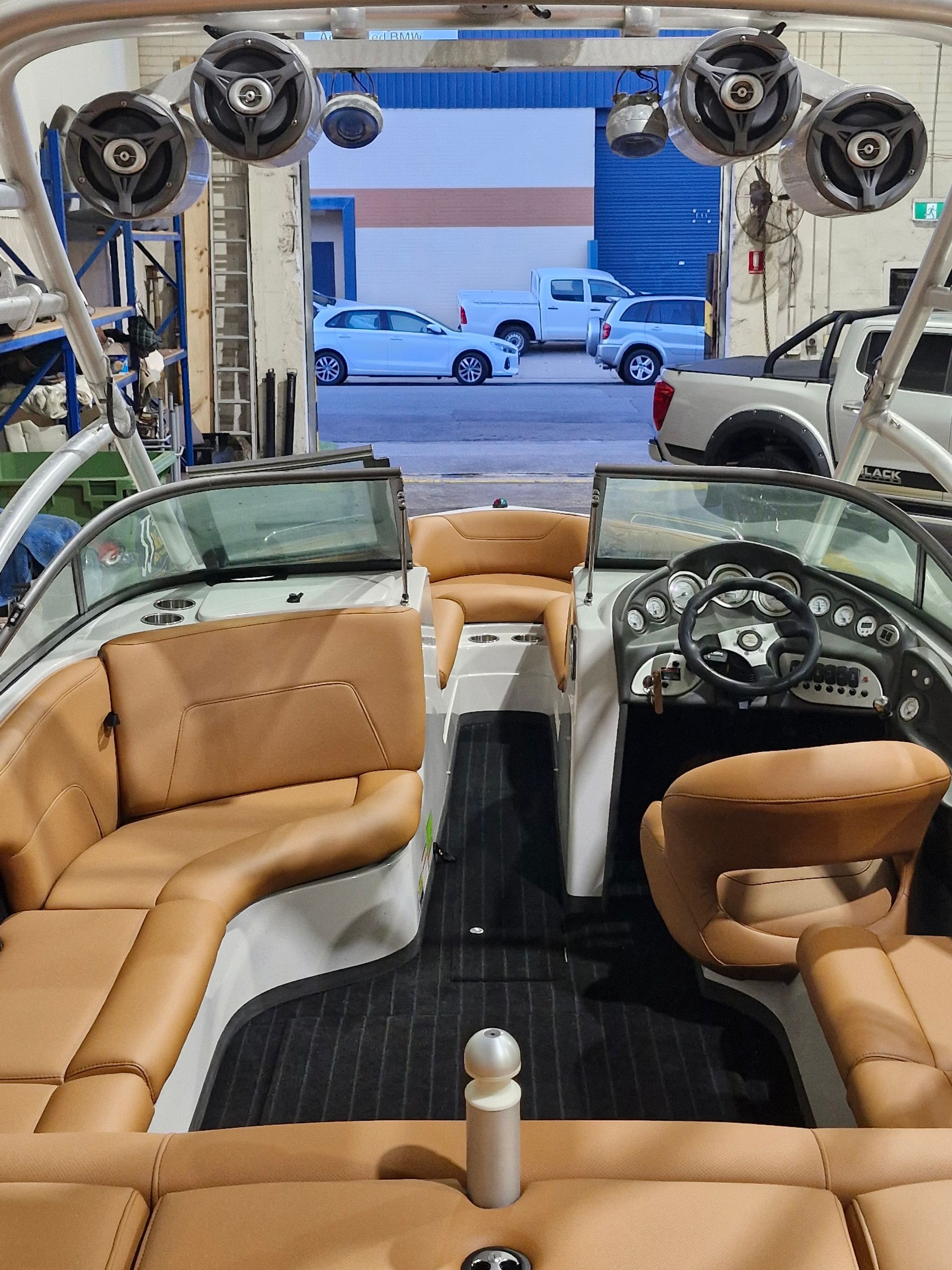 Interior view of a boat featuring tan leather seating, a steering wheel, and four speakers mounted on a white arch — Tidy Trim Newcastle in Carrington, NSW