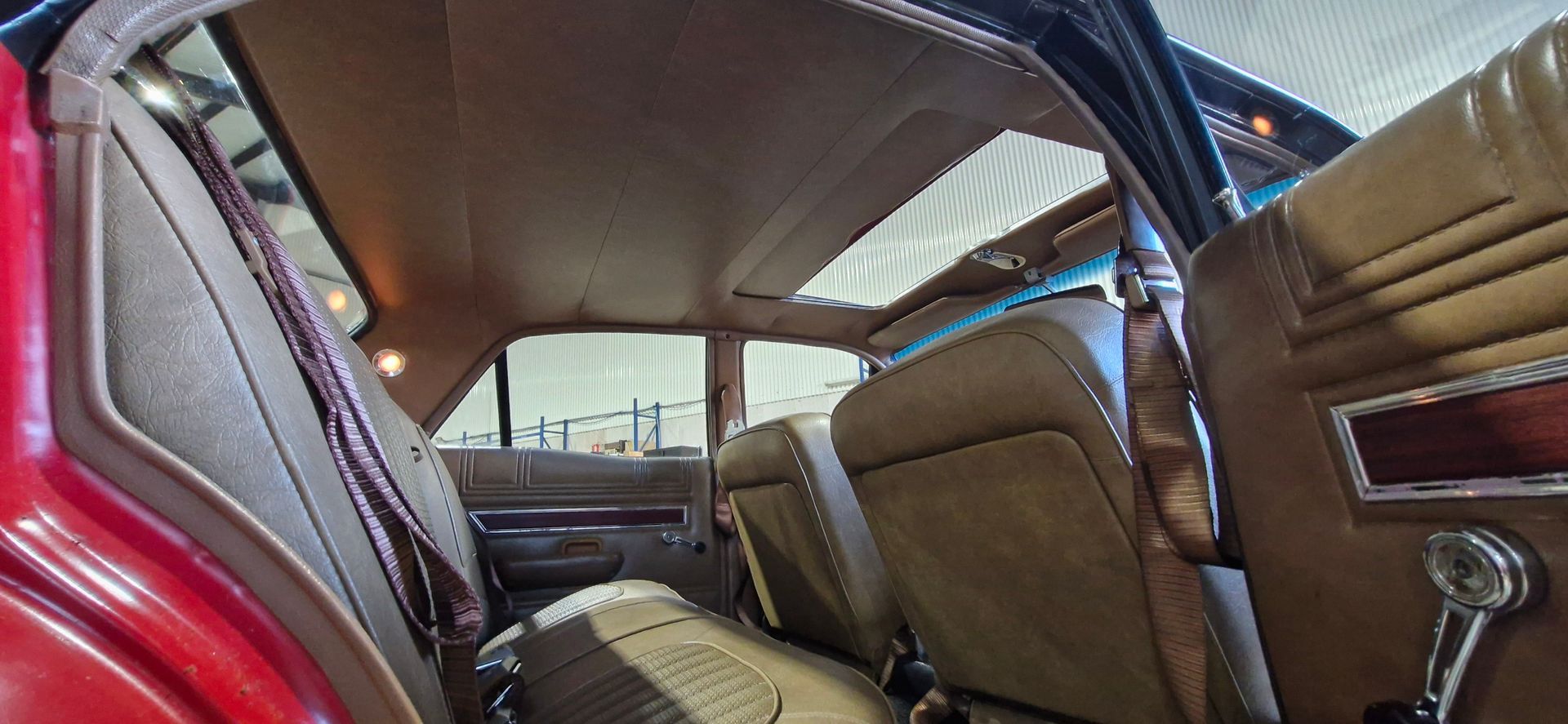 The tan-coloured interior of a vintage car, featuring vinyl seats, a textured headliner, and a metal door handle — Tidy Trim Newcastle in Carrington, NSW