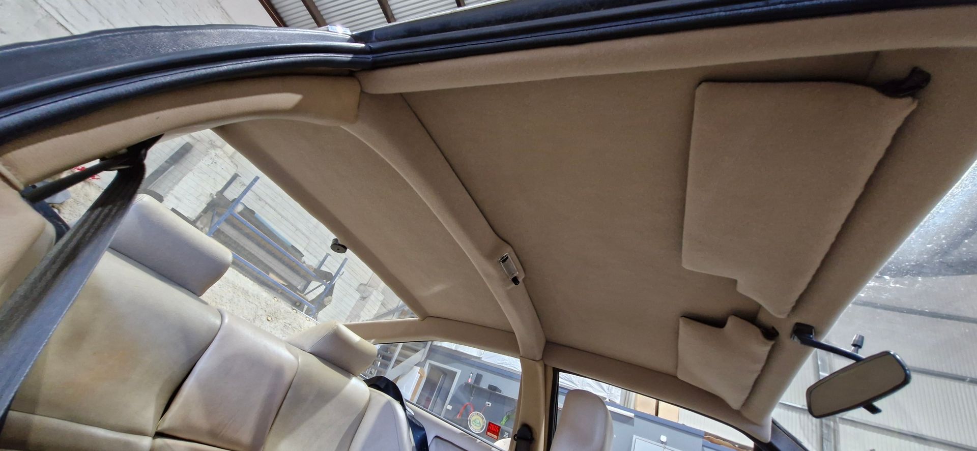 The beige-coloured interior ceiling and headliner of a car, including the sun visors and a rearview mirror — Tidy Trim Newcastle in Carrington, NSW