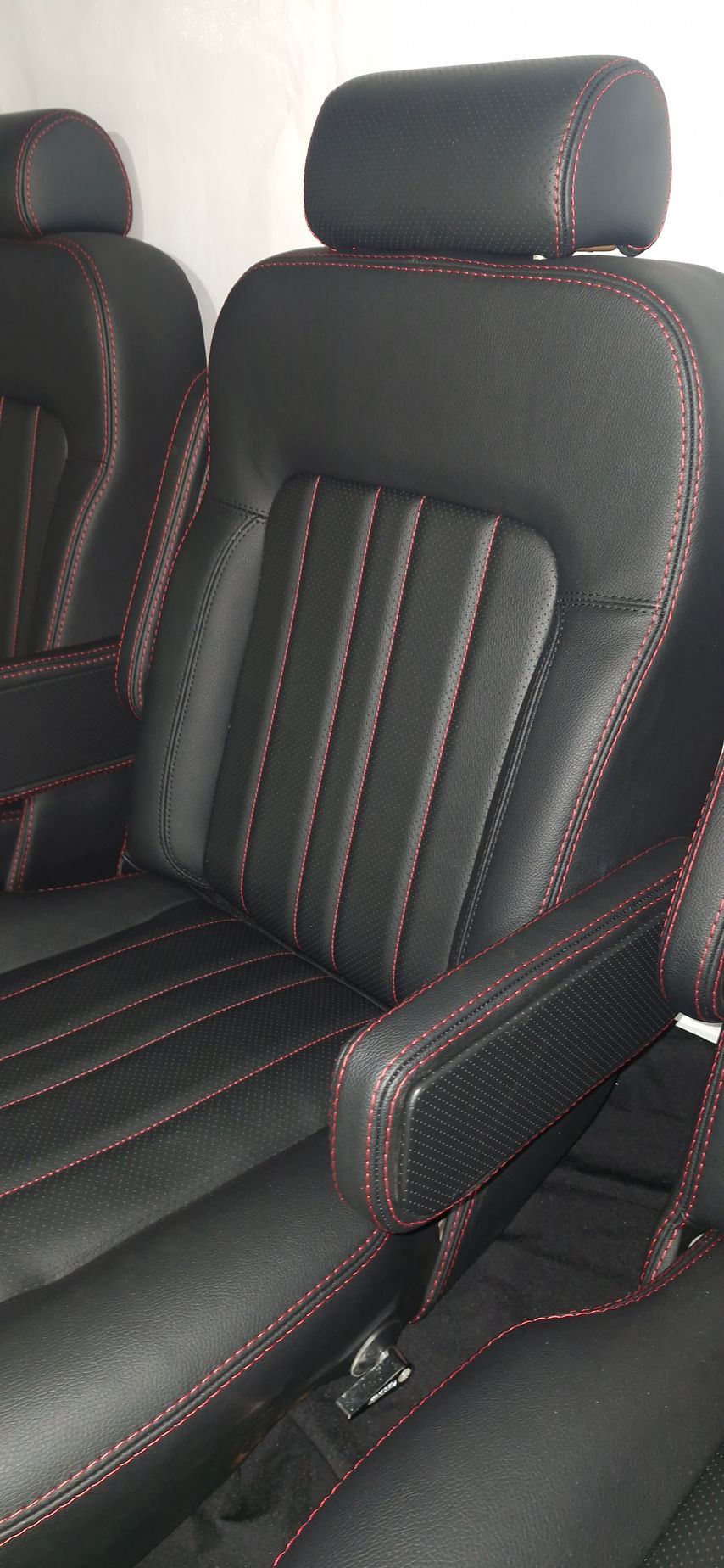 Close-up of black leather vehicle seats featuring red stitched details, vertical panelling — Tidy Trim Newcastle in Carrington, NSW