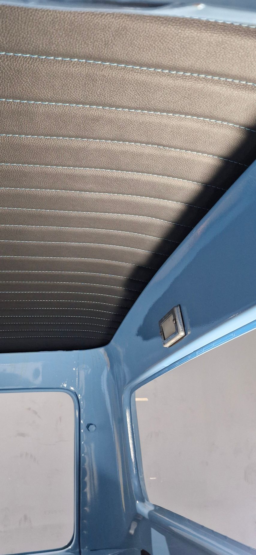 Interior view of a vehicle showing a textured grey headliner and light blue metal roof framing with a small cabin light  — Tidy Trim Newcastle in Carrington, NSW