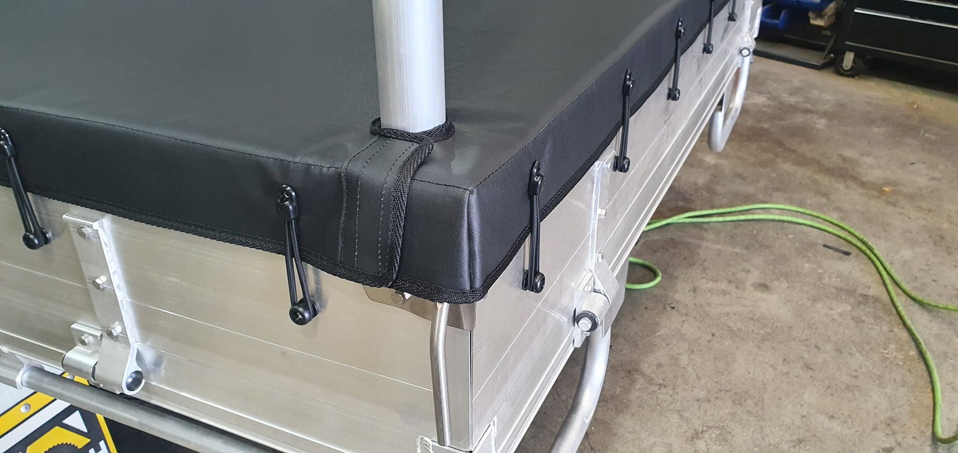 A Black Tarp Secured To A Silver Trailer Bed With Black Fasteners — Tidy Trim Newcastle in Carrington, NSW