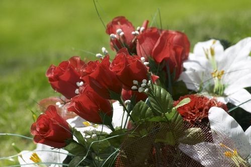 A bouquet of red roses and white lilies is sitting in the grass.