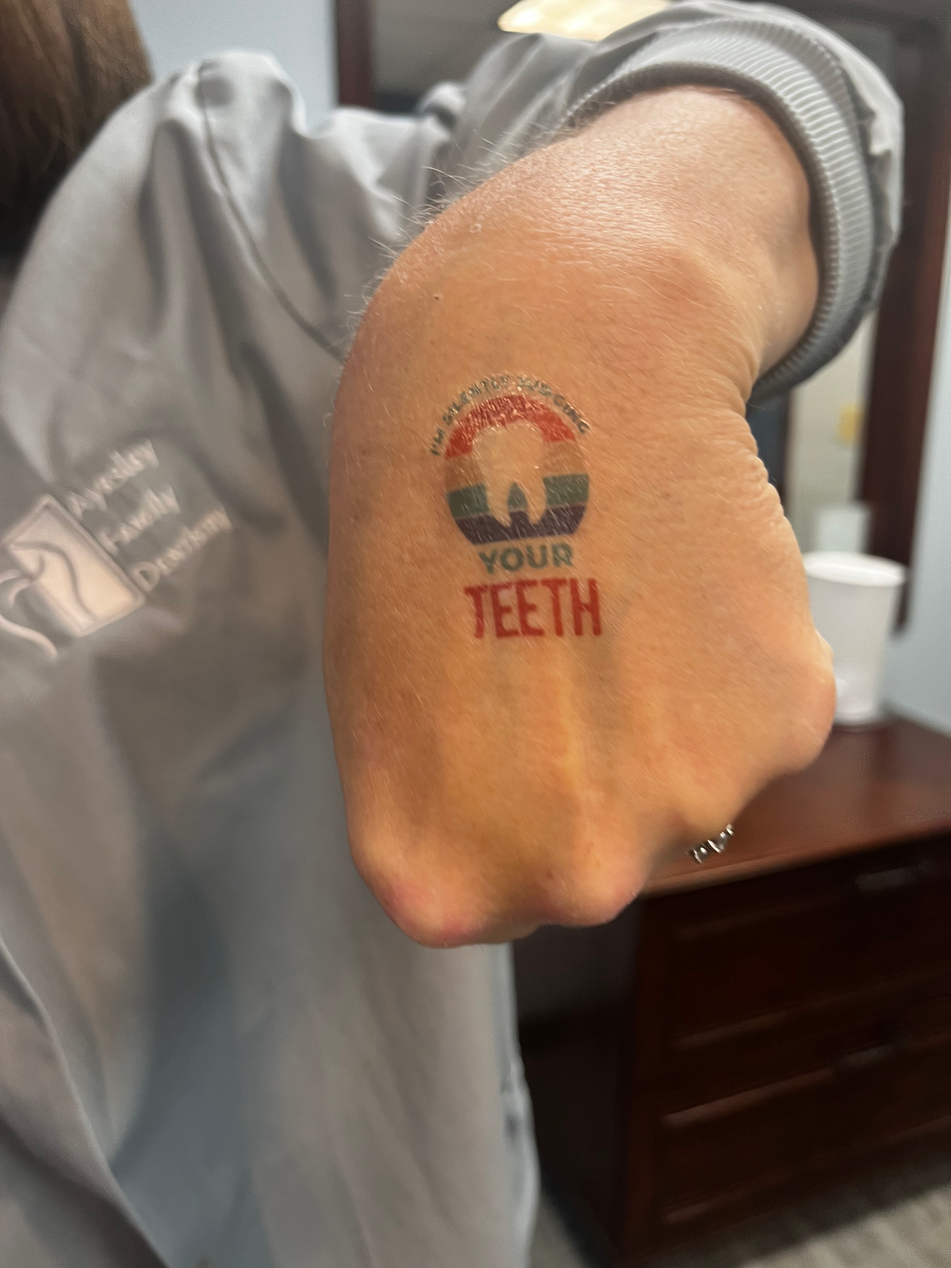 Person's fist with temporary tattoo of a tooth in a retro design, with the words