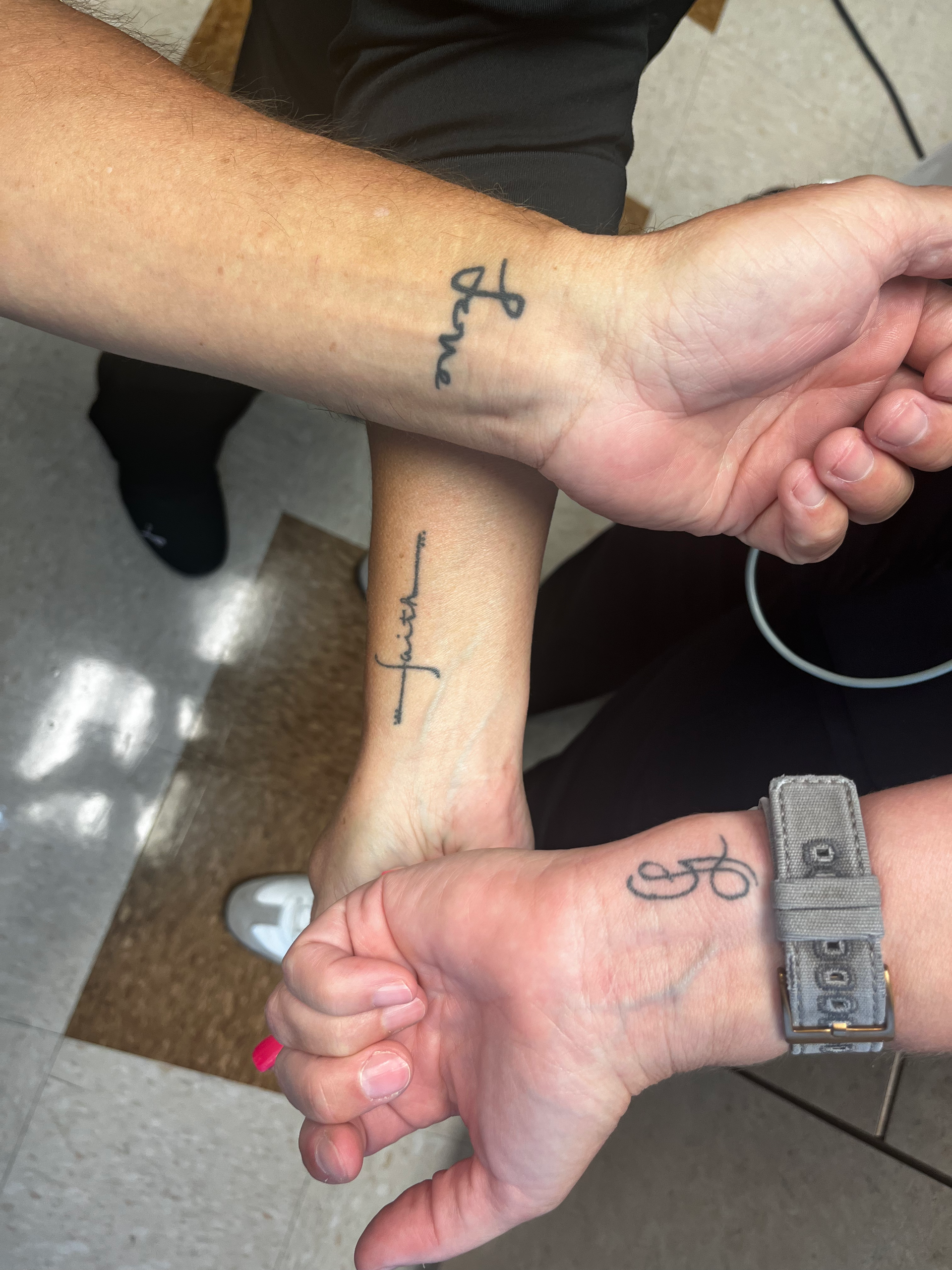 Three people's wrists with tattoos: