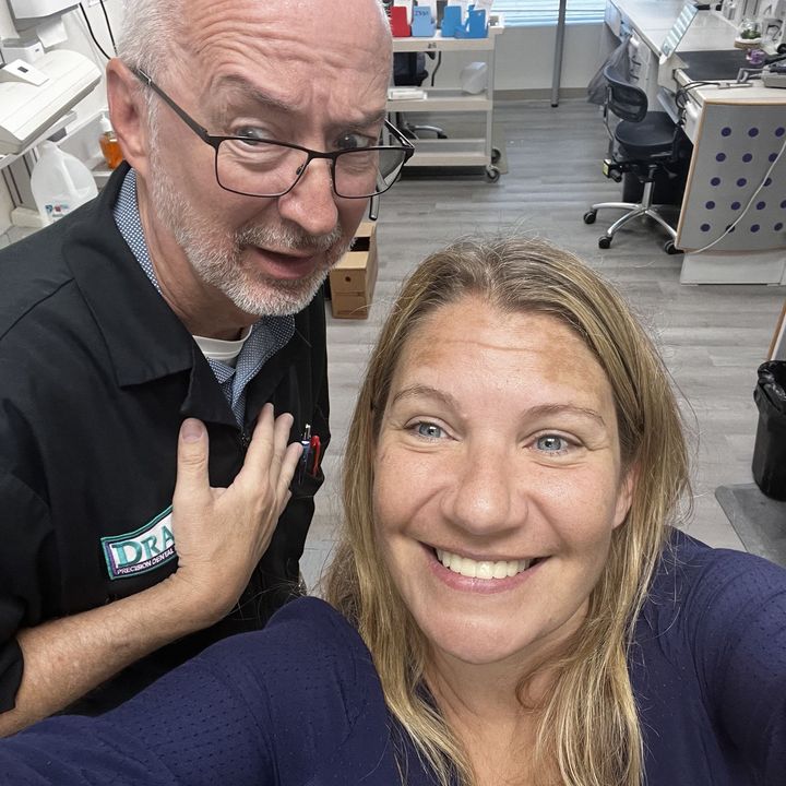 Man and woman taking a selfie in a lab, man with glasses, woman smiling, both with fair skin.