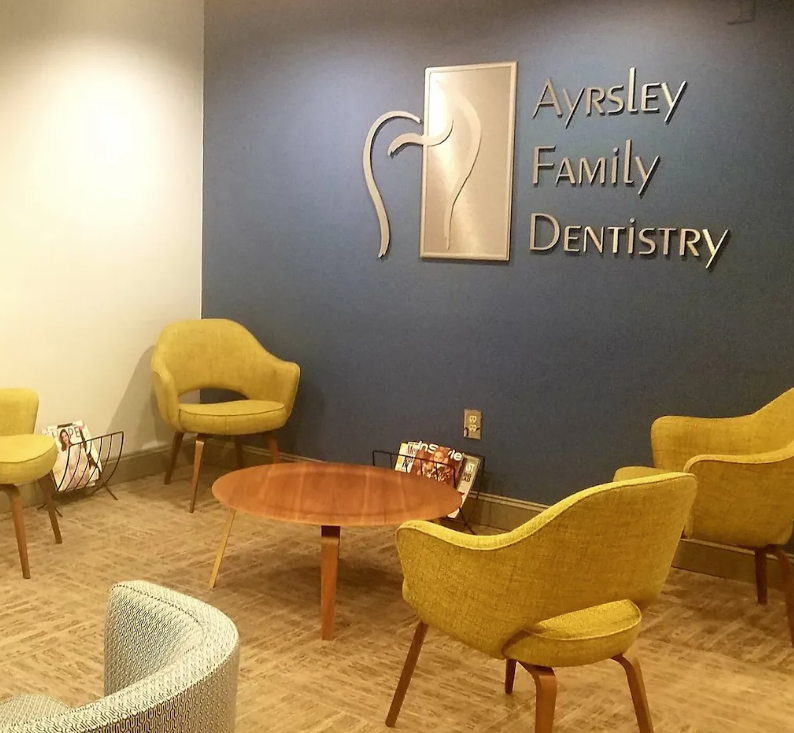 A waiting room for ayrsley family dentistry with chairs and a table