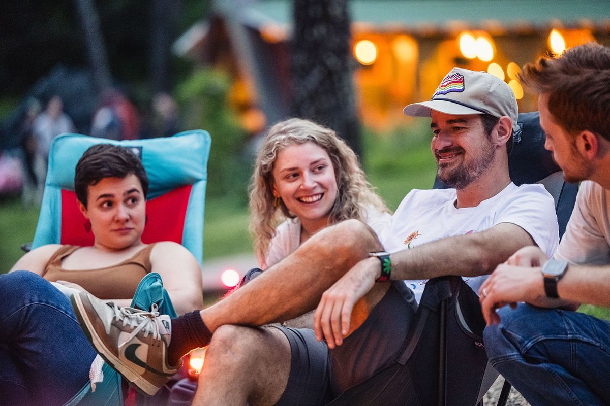 Two men and two women gather around a fire pit.