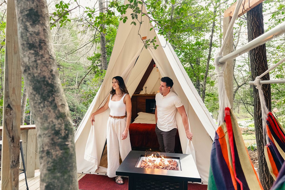 A man and woman walk out of a white tent.