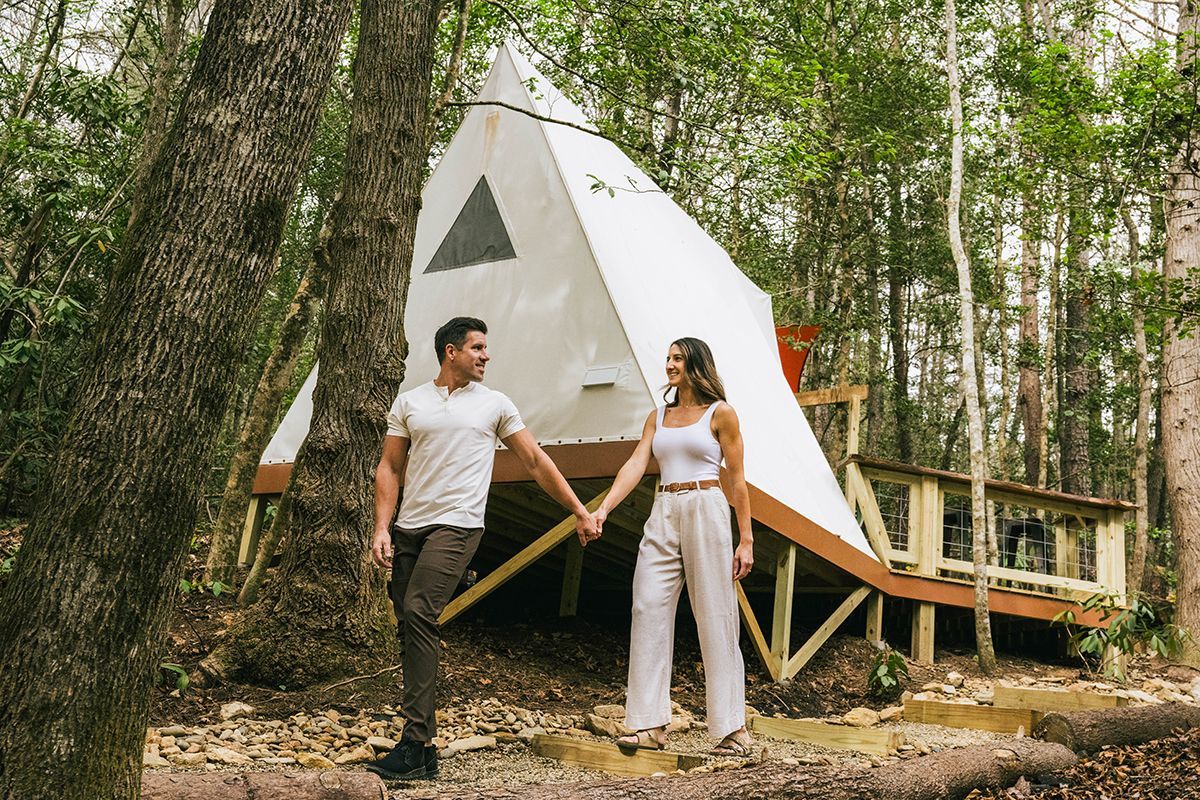 A couple stands outside a camping villa