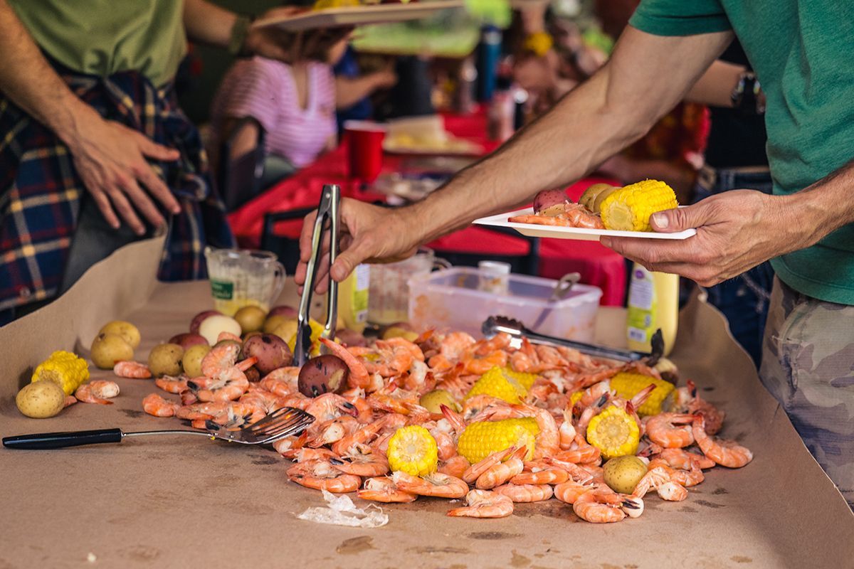 Shrimp, potatoes and corn are spread out on a dining table.