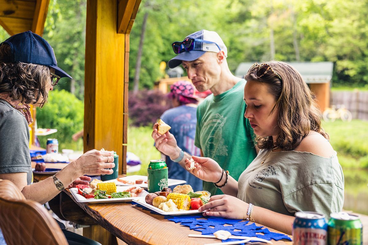 Three people eat at an outdoor counter.