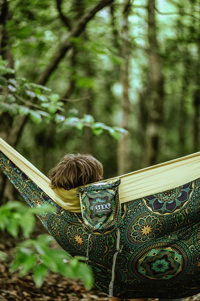 A person relaxes in a hammock in the woods.