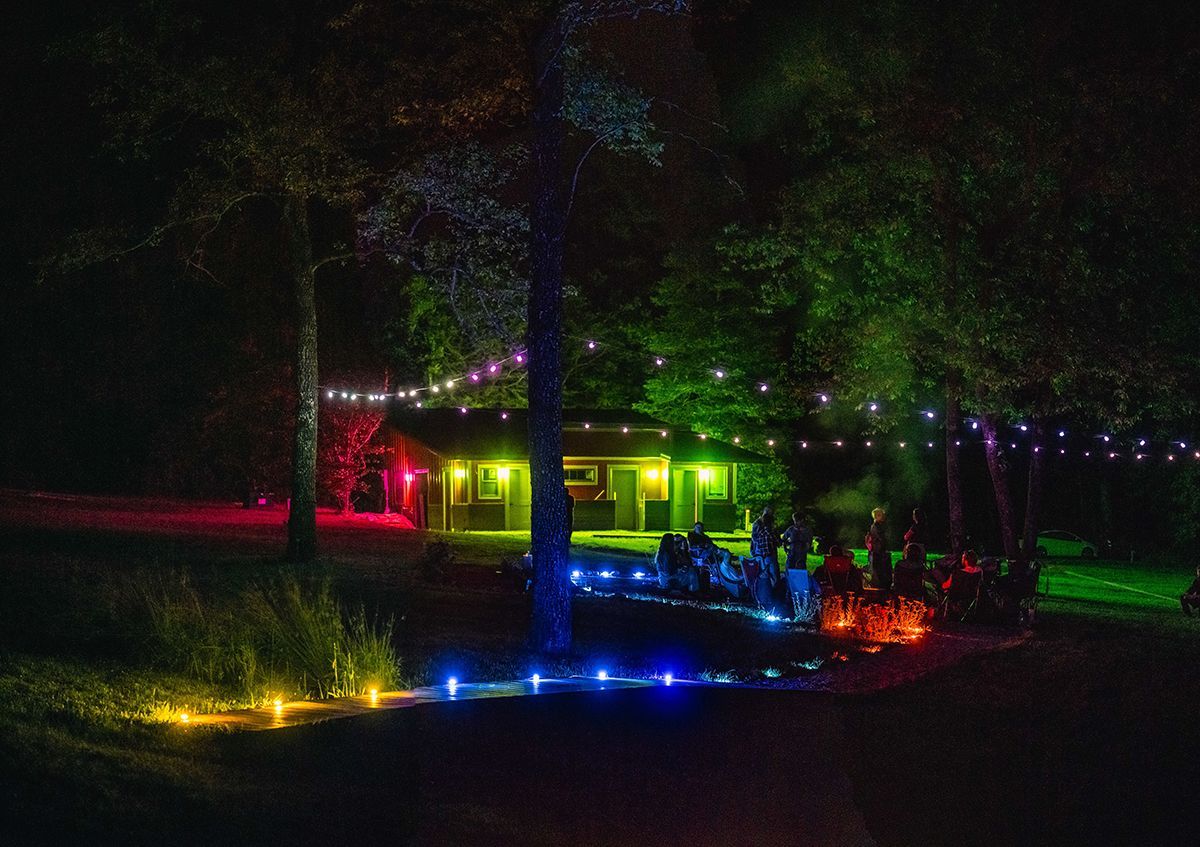 Pathways at a campground are lit with multi-colored lights.