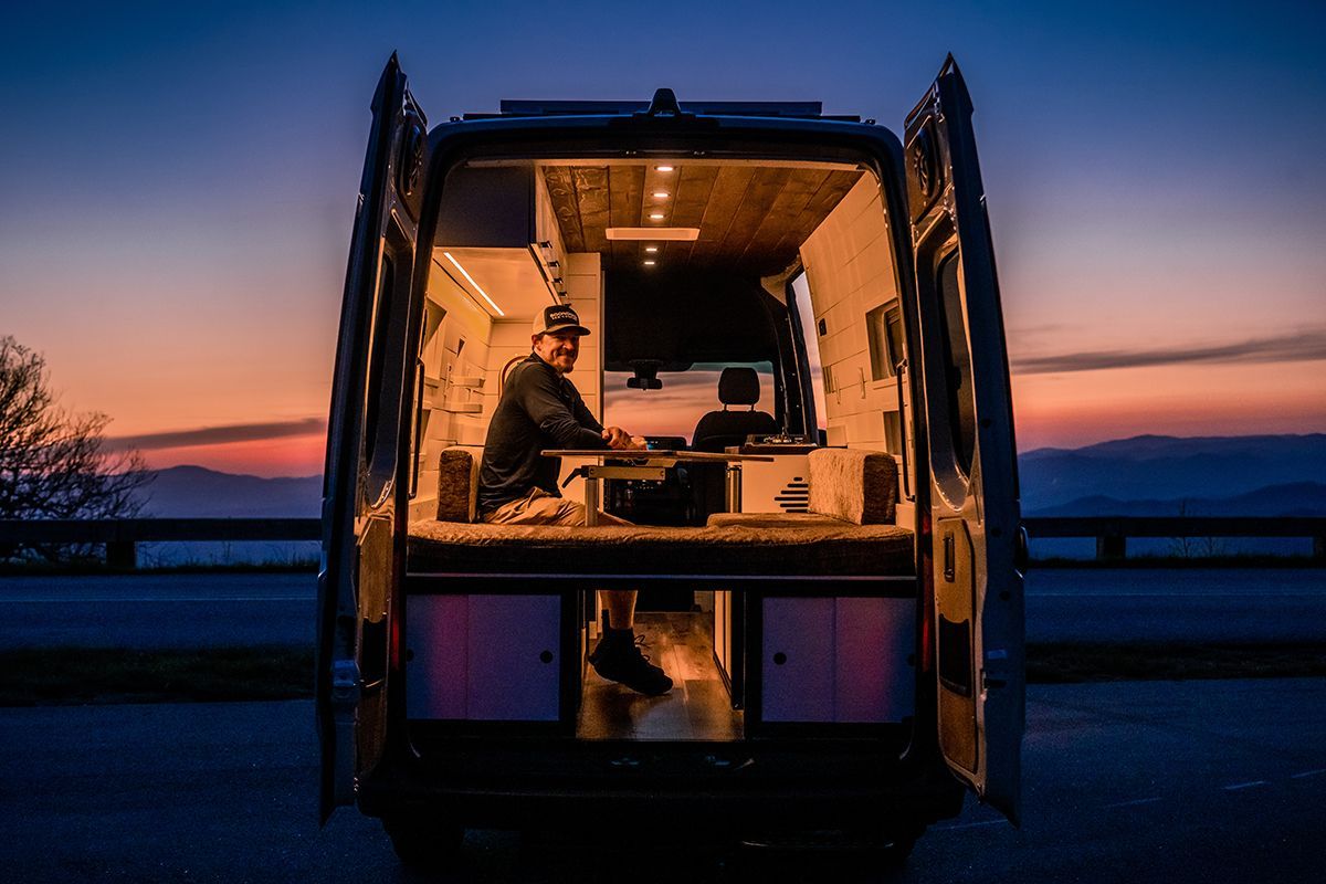 A man sits inside a camping van on the blue