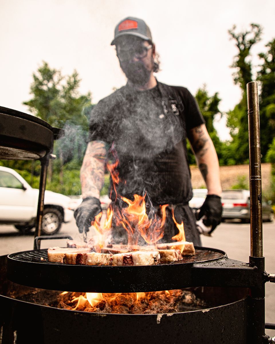 A man cooks over an open fire grill.