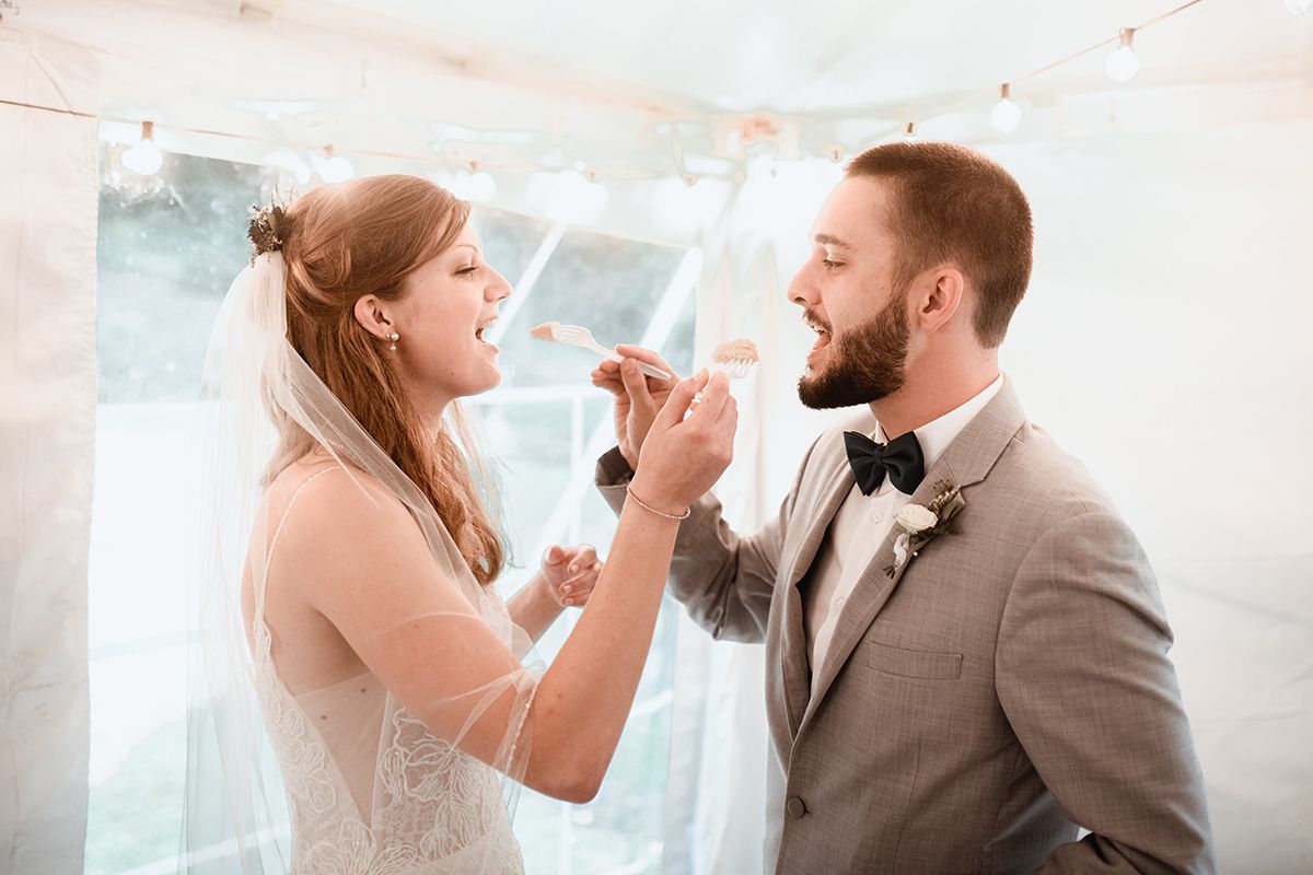 A bride and groom are standing next to each other in the woods.