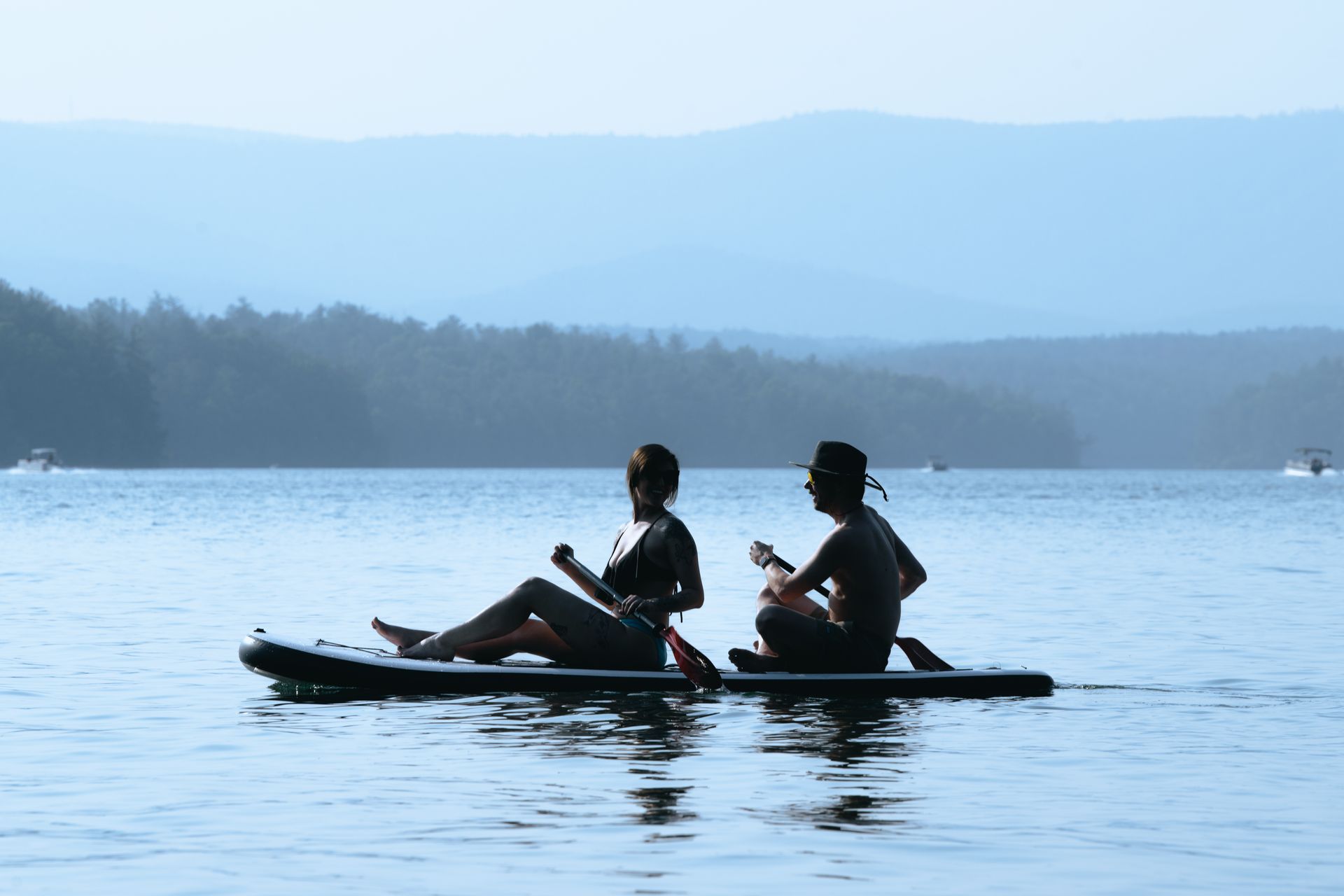 Two people paddle on a lake.
