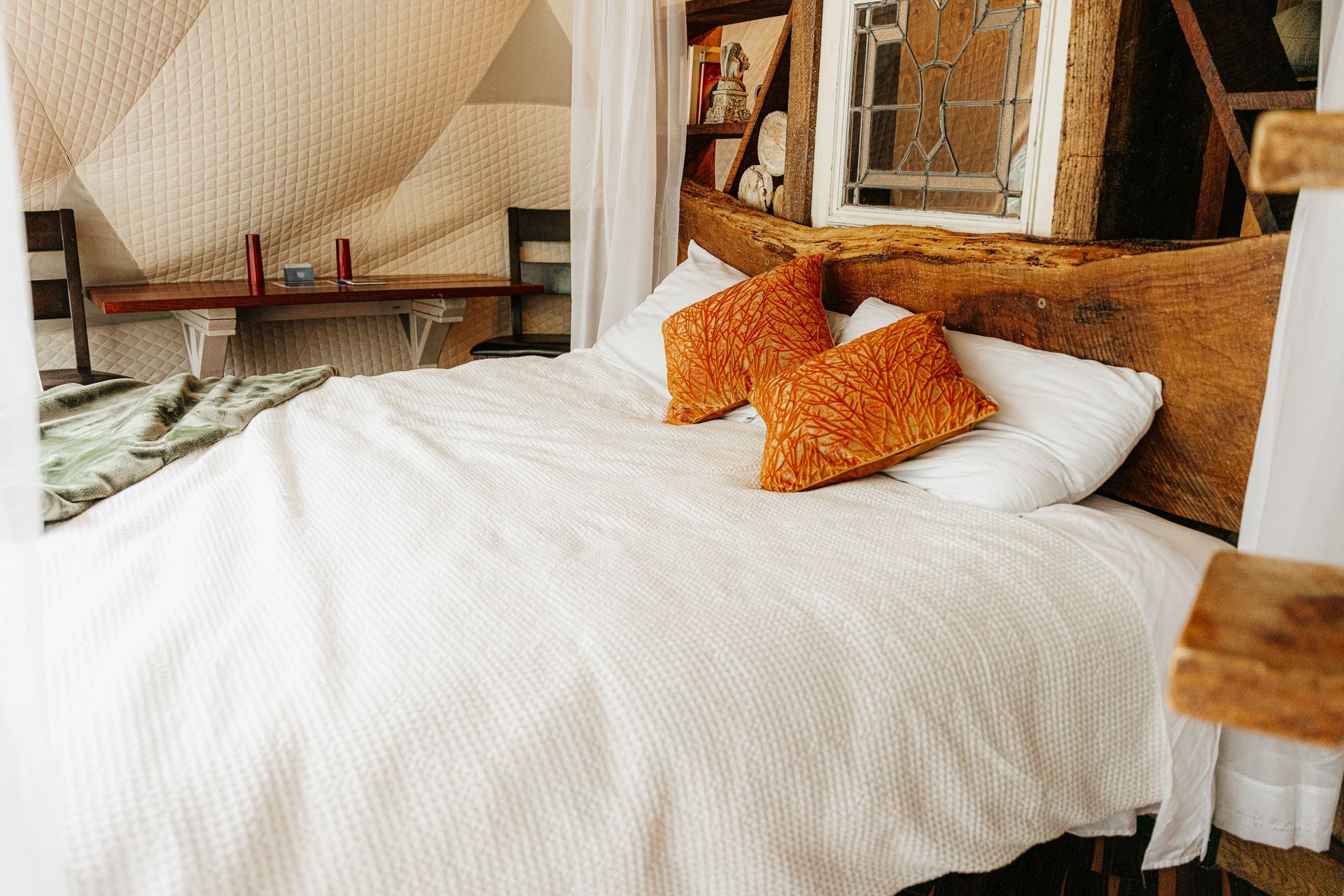 A bedroom with a bed and a lamp hanging from the ceiling.