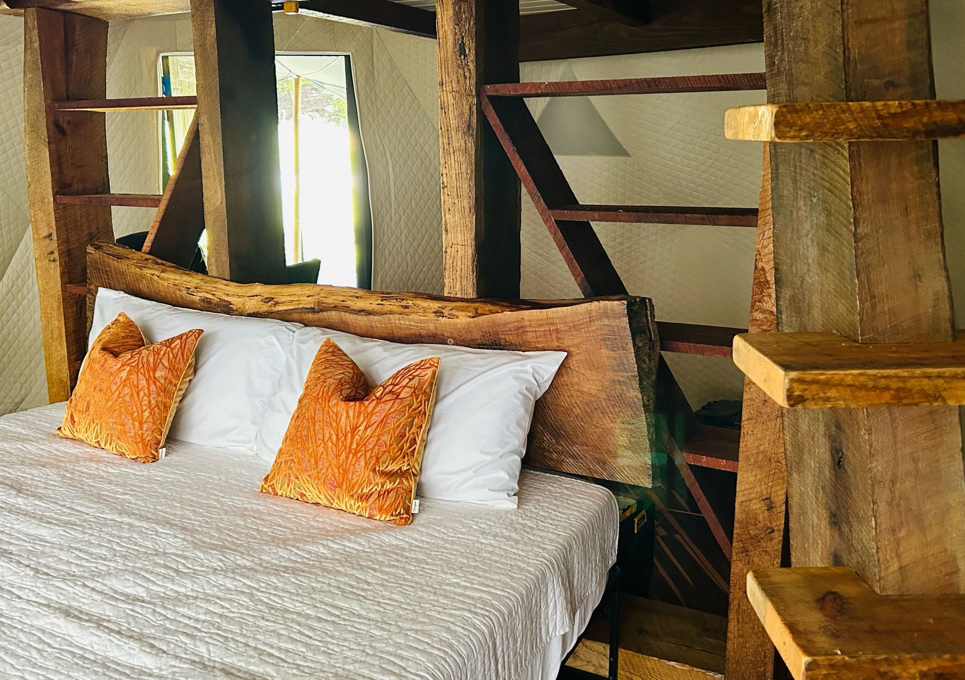 Bedroom with a wooden frame bed, white bedding, orange pillows, and wooden shelves.