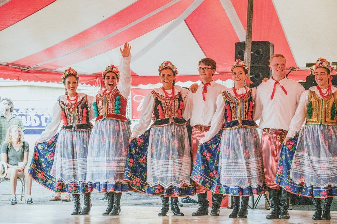 A group of people in traditional clothes are dancing on a stage.