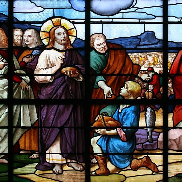 A stained glass window shows Jesus feeding the 500. 