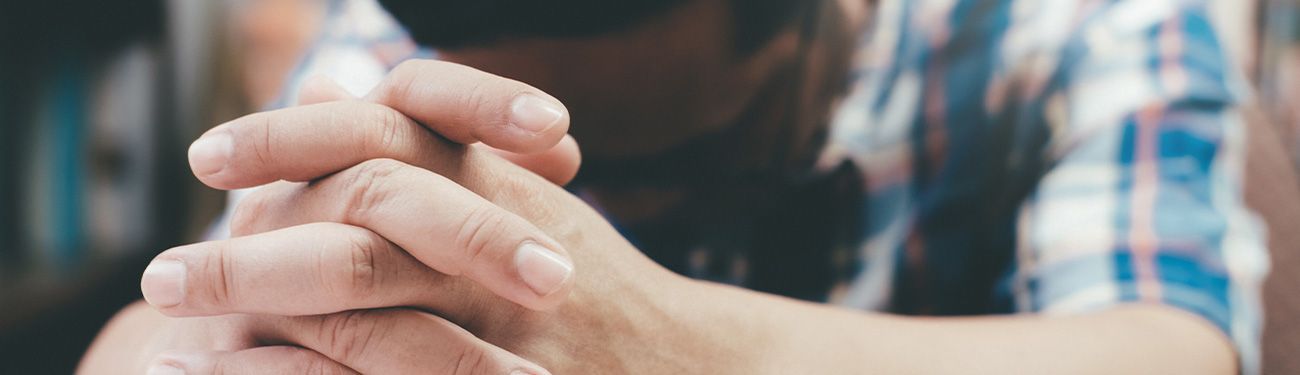 A woman is praying with her hands folded in prayer.