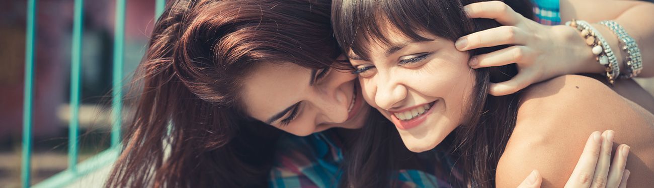 Two women are hugging each other and smiling.